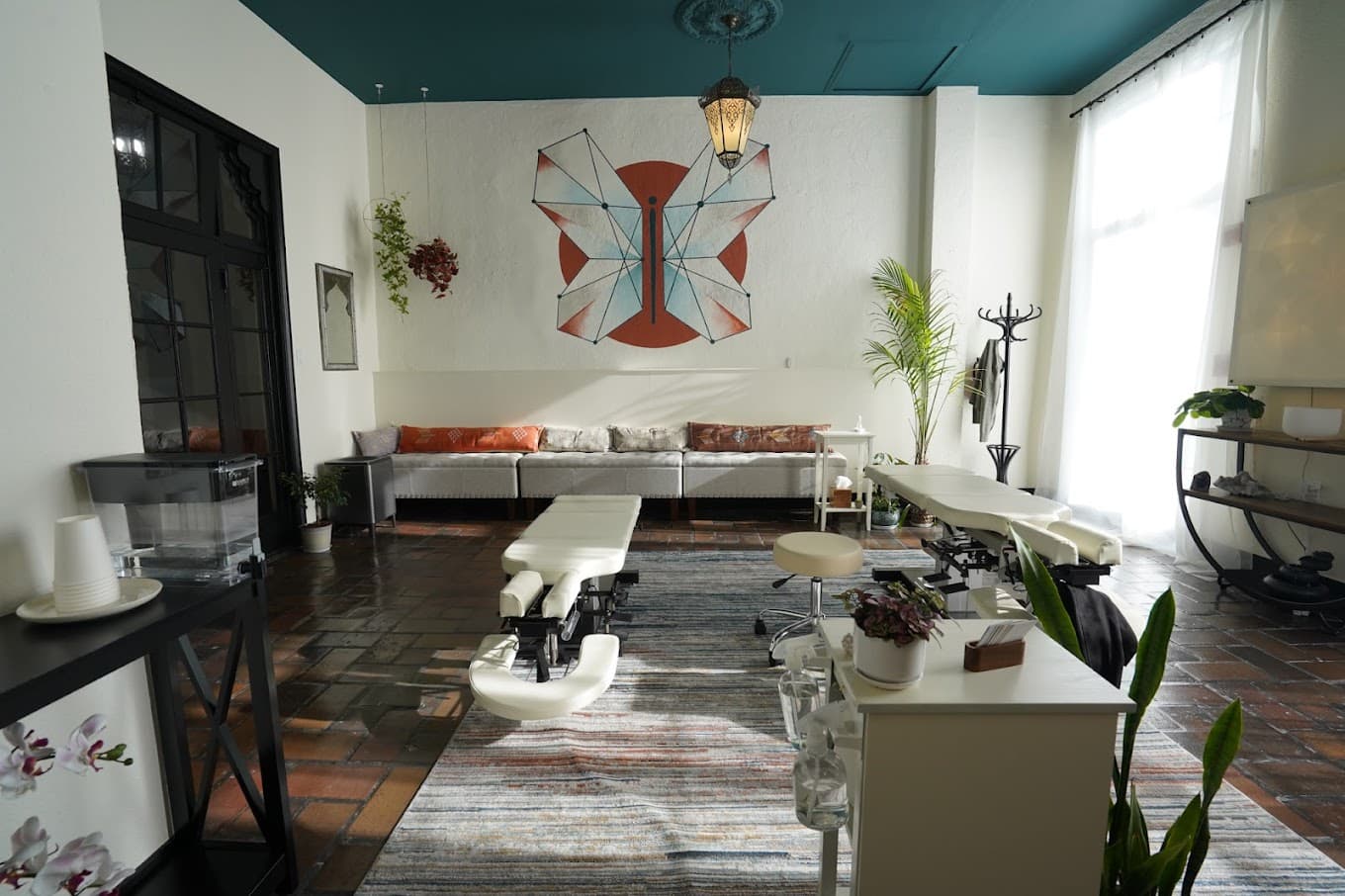 Anam Cara Chiropractic clinic interior — adjustment tables, butterfly mural, and Moroccan-inspired design